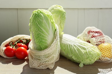 Photo of Fresh Chinese cabbages and other vegetables on light wooden table indoors