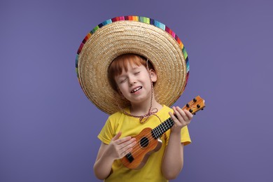 Cute boy in Mexican sombrero hat playing ukulele and singing on violet background, space for text