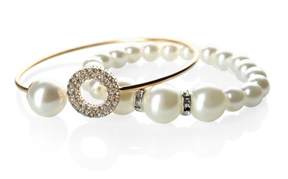 Photo of Elegant pearl and golden bracelets on white background