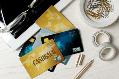 Image of Cashback and credit cards, tablet and stationery on white wooden table, flat lay