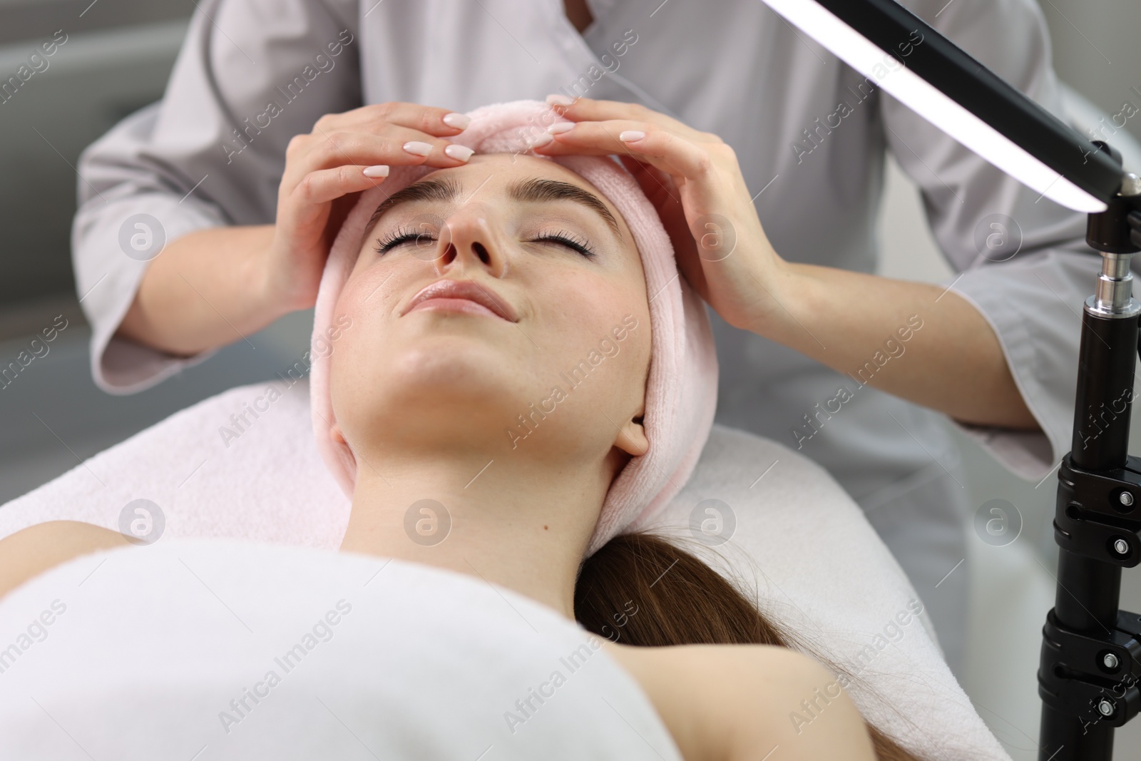 Photo of Cosmetologist making face massage to client in clinic, closeup