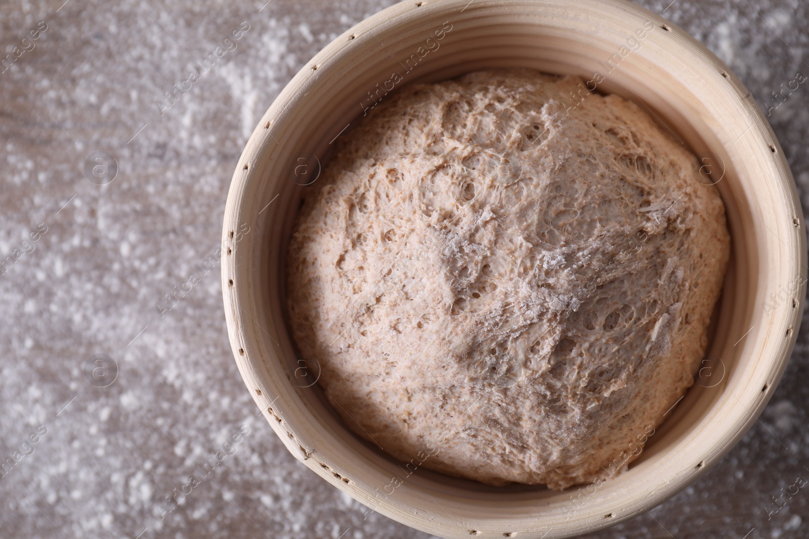 Photo of Fresh sourdough in proofing basket on table, top view. Space for text