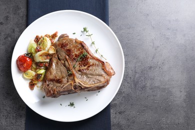 Photo of Delicious fried beef meat and vegetables on grey table, top view. Space for text