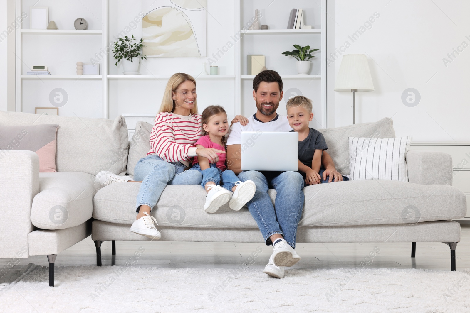 Photo of Happy family with laptop spending time together on sofa at home