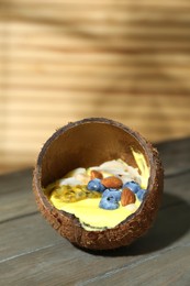 Tasty smoothie bowl with fresh blueberries and almonds served in coconut shell on wooden table