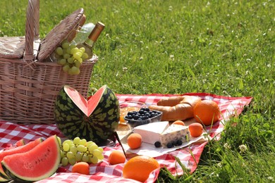 Photo of Picnic blanket with delicious food and wine outdoors on summer day