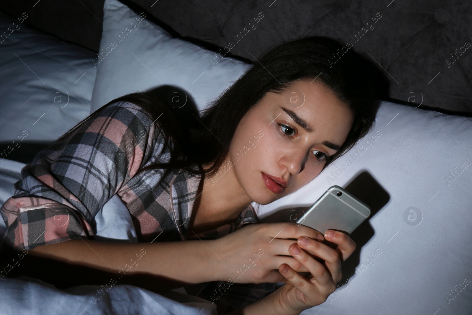 Photo of Sad lonely woman using smart phone in bed