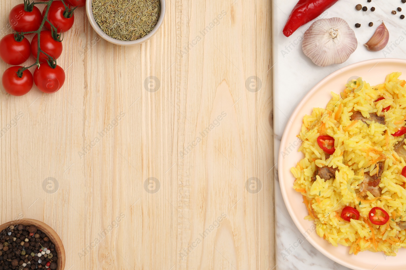 Photo of Delicious pilaf with meat and ingredients on wooden table, flat lay. Space for text