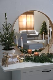 Photo of Mirror over chest of drawers with Christmas decor in room. Interior design