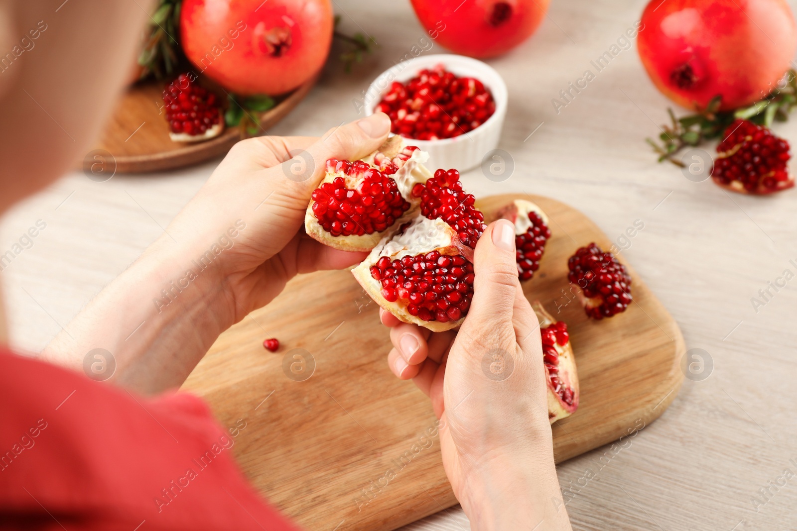 Photo of Woman with delicious ripe pomegranate at wooden table, closeup