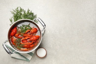 Photo of Fresh delicious crayfishes in pot on light grey table, flat lay. Space for text