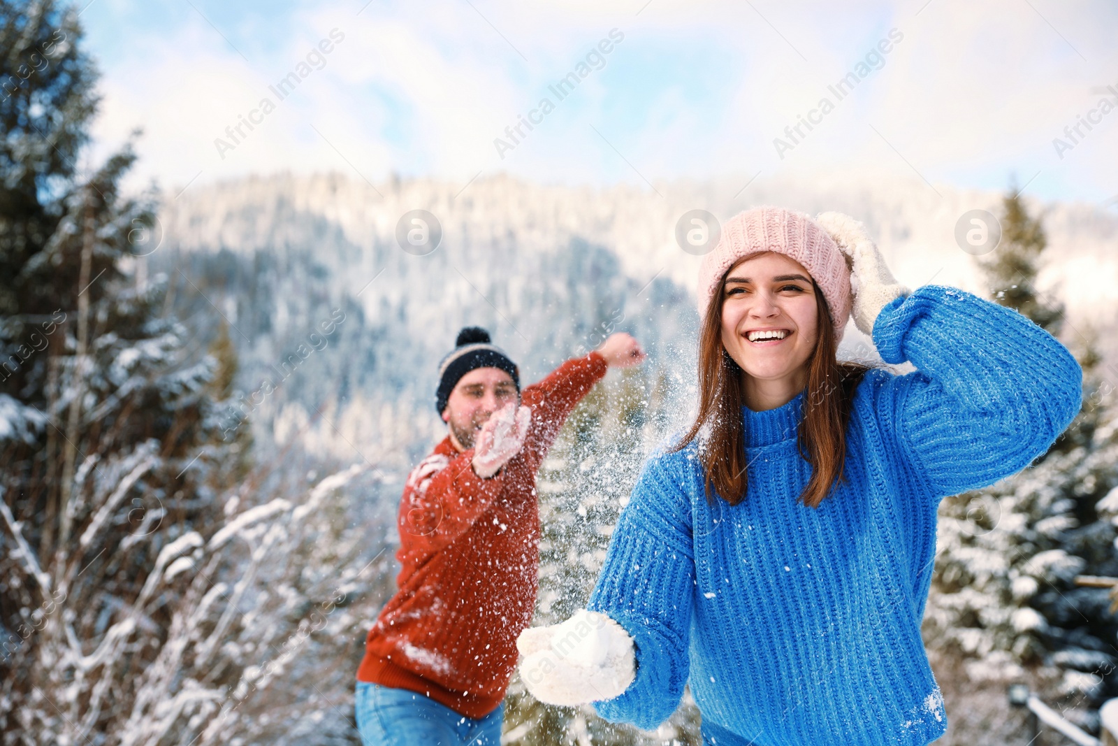 Photo of Happy couple playing snowballs outdoors. Winter vacation