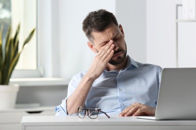 Photo of Man suffering from eyestrain at desk in office