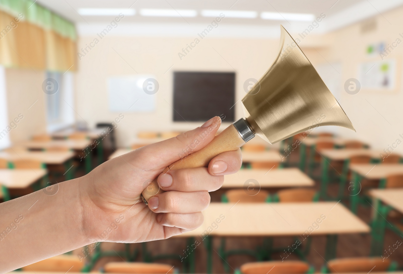 Image of Woman with school bell in empty classroom, closeup