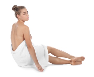 Young woman with soft towel sitting on white background