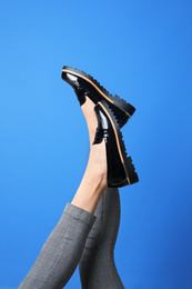 Woman wearing stylish shoes on blue background, closeup