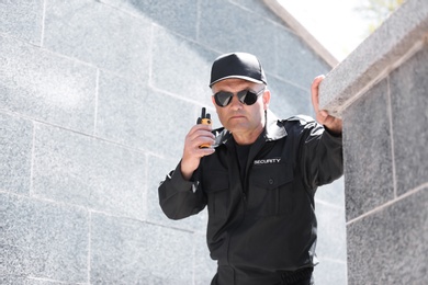 Photo of Male security guard using portable radio transmitter outdoors