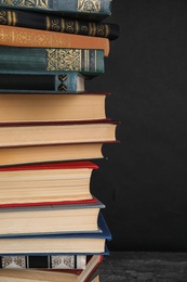 Stack of hardcover books on grey stone table against black background