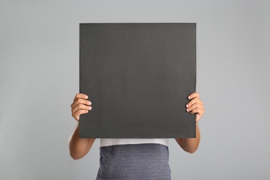 Photo of Man holding black blank poster on grey background. Mockup for design