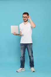 Serious man using laptop on light blue background