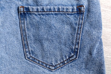Photo of Stylish light blue jeans on white wooden background, closeup of back pocket