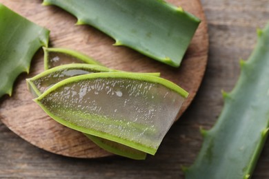 Photo of Slices of fresh aloe vera leaves with gel on wooden table, flat lay. Space for text