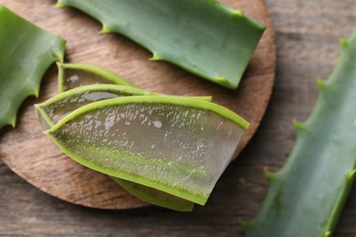 Slices of fresh aloe vera leaves with gel on wooden table, flat lay. Space for text