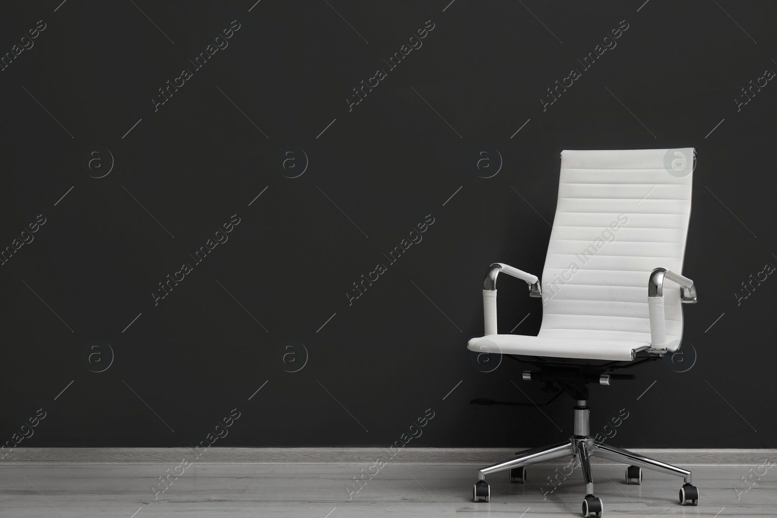 Photo of Comfortable office chair near black wall indoors. Space for text