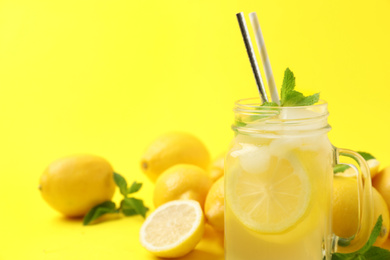 Natural freshly made lemonade with mint on yellow background, closeup. Summer refreshing drink