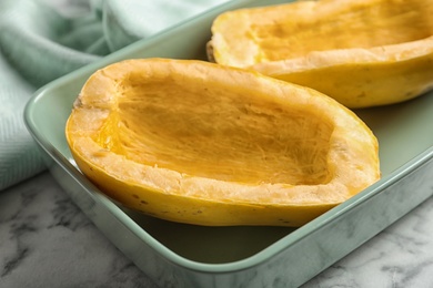 Photo of Baking dish with cut spaghetti squash on table