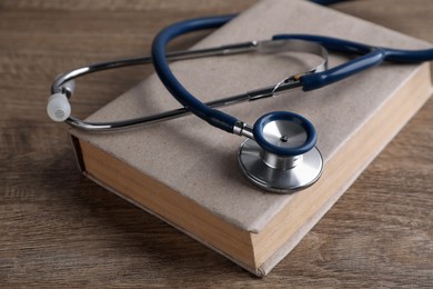 Photo of Student textbook and stethoscope on wooden table. Medical education