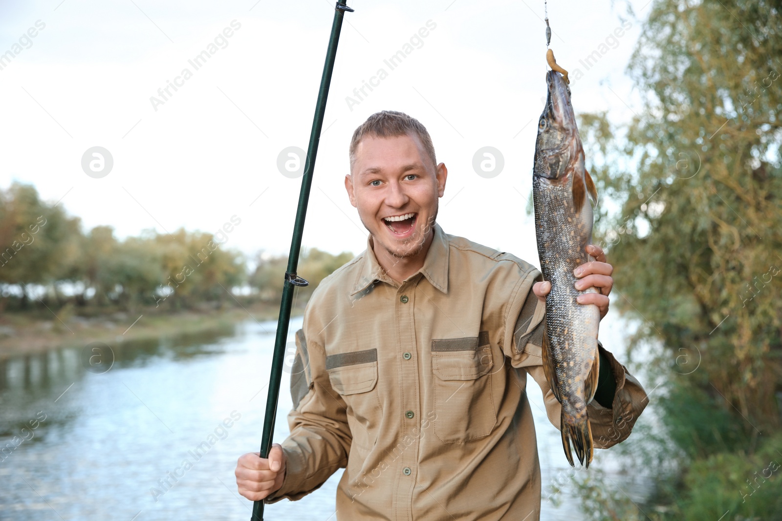 Photo of Man with rod and catch fishing at riverside. Recreational activity