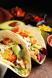 Photo of Delicious tacos with shrimps and cheese on wooden table, closeup