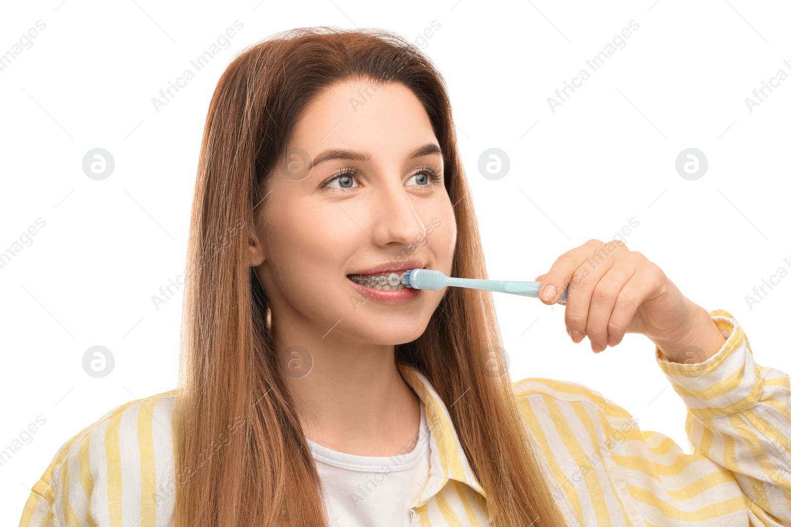 Photo of Smiling woman with dental braces cleaning teeth on white background
