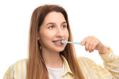 Photo of Smiling woman with dental braces cleaning teeth on white background