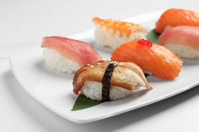 Photo of Plate with delicious nigiri sushi on white table, closeup