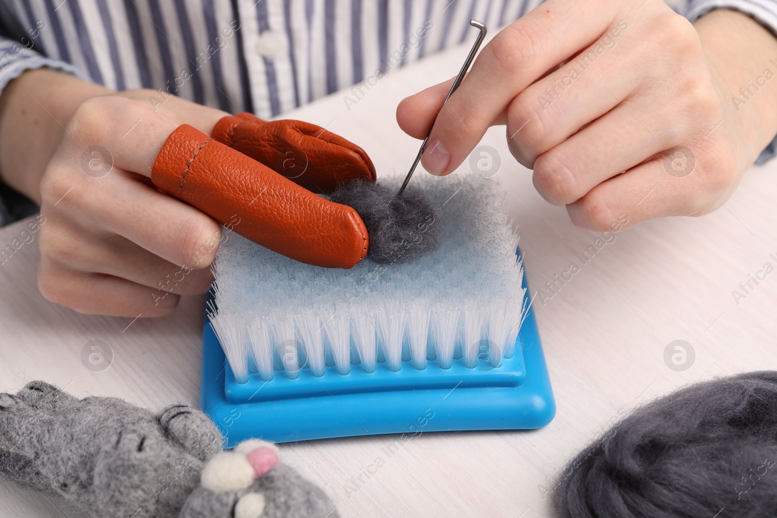 Photo of Woman felting from wool at light wooden table, closeup