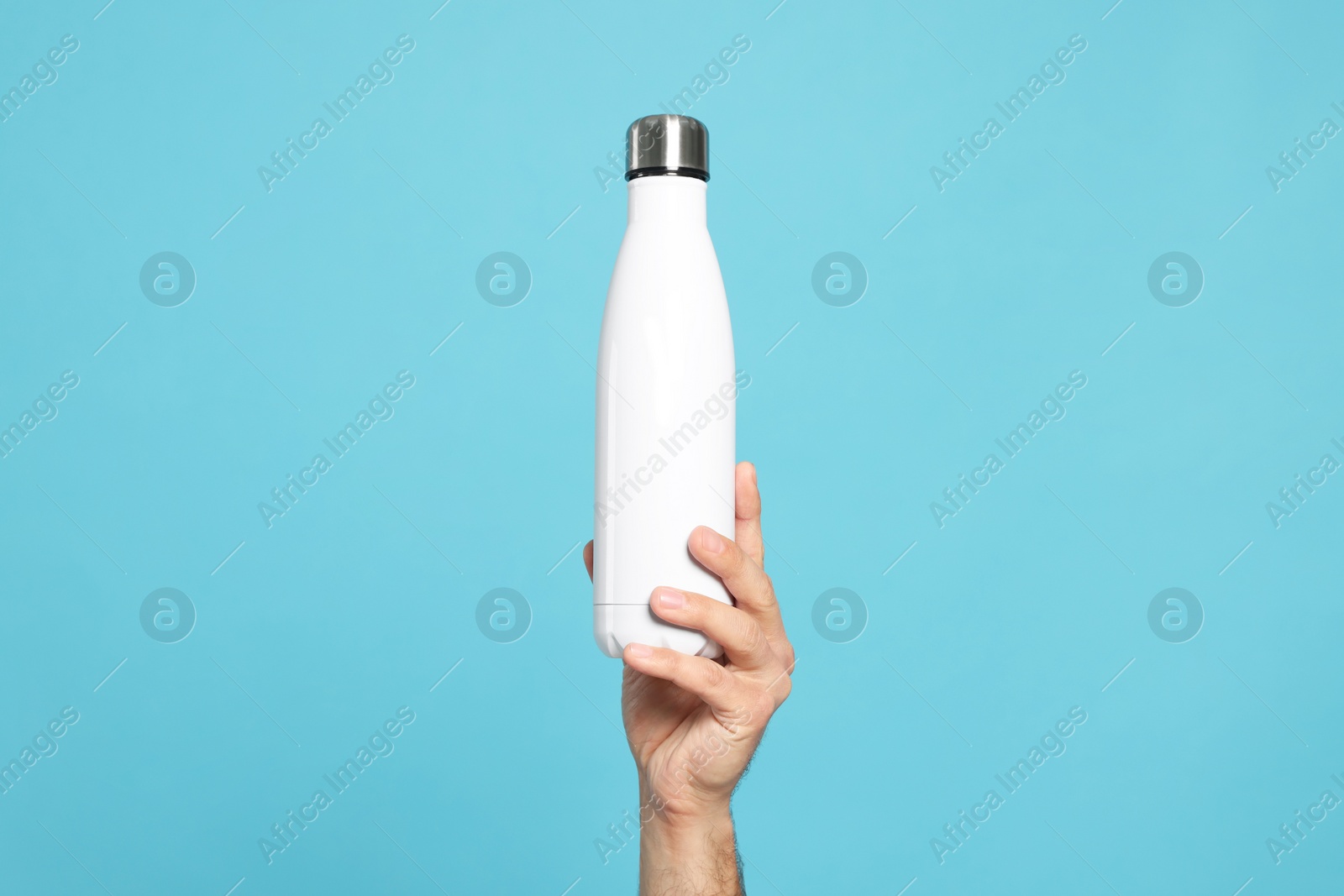 Photo of Man holding thermo bottle on light blue background, closeup