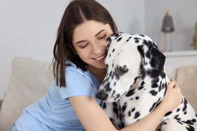 Photo of Beautiful woman hugging her adorable Dalmatian dog at home. Lovely pet