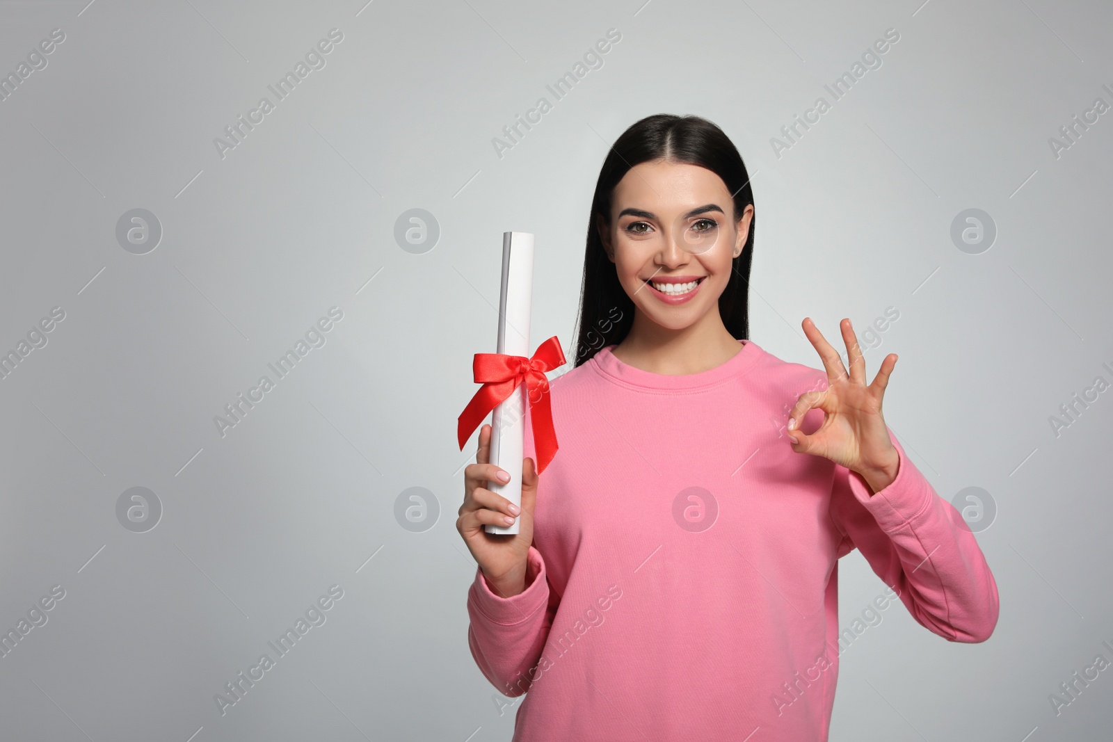 Photo of Happy woman with diploma on light grey background. Space for text
