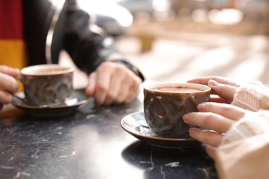 Couple enjoying tasty aromatic coffee at table, closeup view