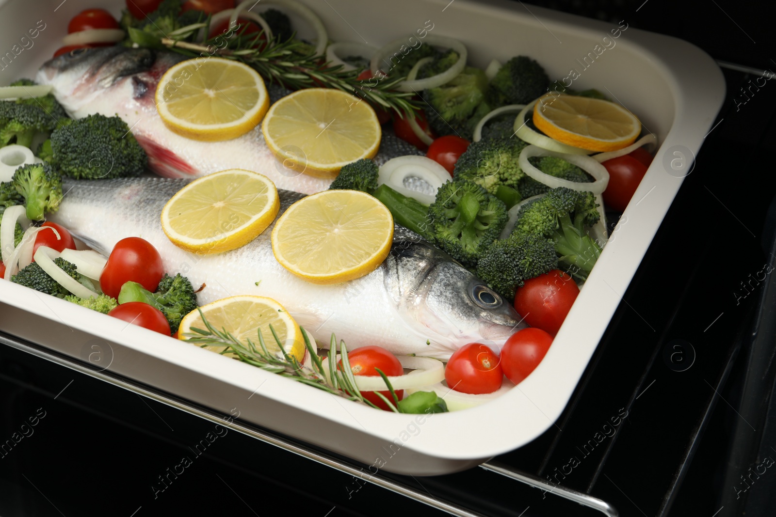 Photo of Raw fish with vegetables and lemon in baking dish into oven