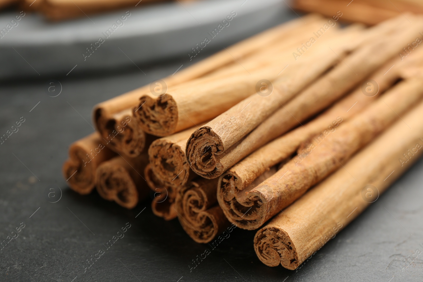 Photo of Aromatic cinnamon sticks on black table, closeup