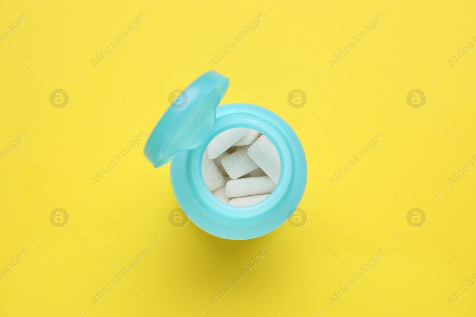 Photo of Jar with chewing gums on yellow background, top view