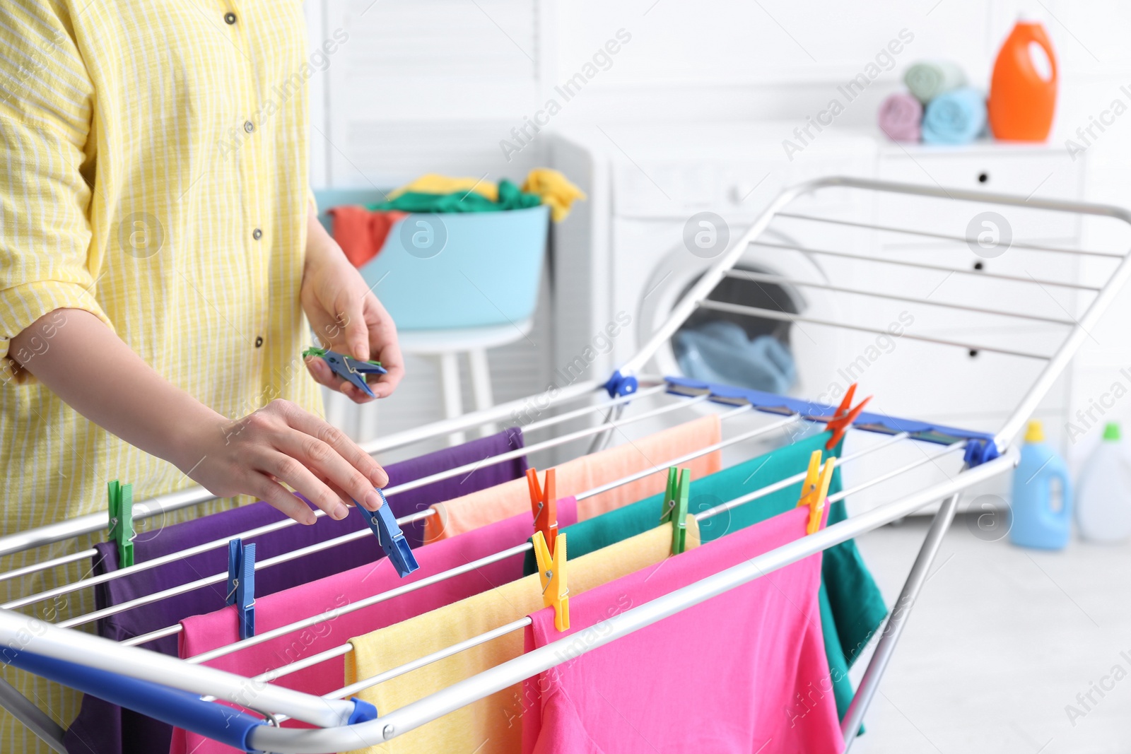 Photo of Woman hanging clean laundry on drying rack in bathroom, closeup