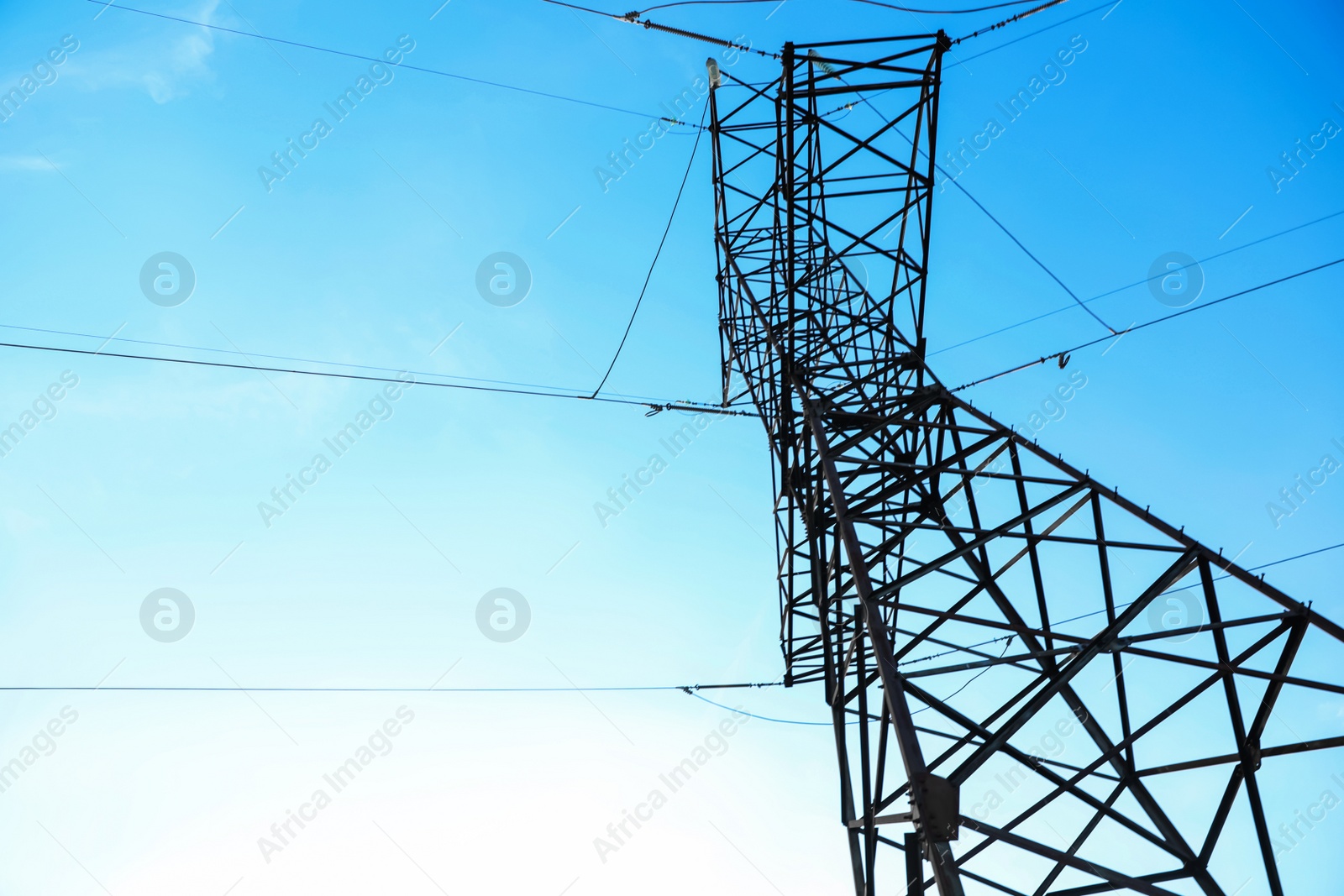 Photo of High voltage tower against beautiful blue sky, low angle view