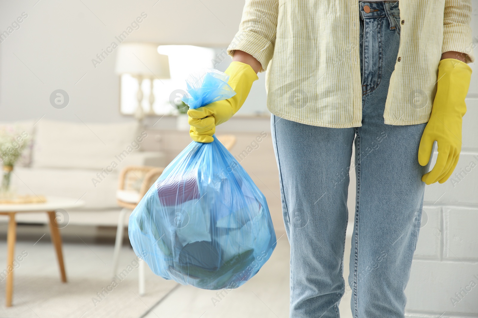 Photo of Woman holding full garbage bag at home, closeup