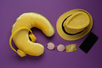 Photo of Flat lay composition with yellow travel pillow and smartphone on purple background