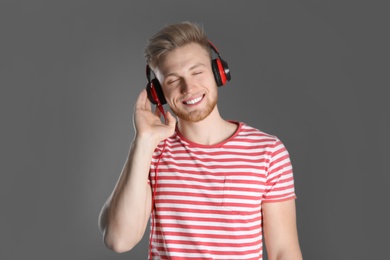 Photo of Handsome young man listening to music with headphones on color background