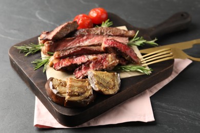 Photo of Delicious grilled beef with vegetables and rosemary served on dark gray table, closeup
